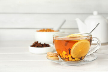 Glass cup of immunity boosting drink on white wooden table, space for text
