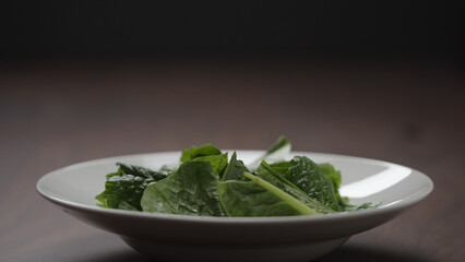 making salad put romaine leaves in white bowl