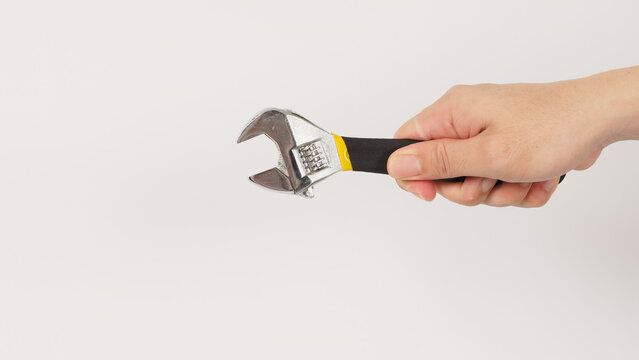 The hand is holding an adjustable wrench isolated on white background. Backhand picture.
