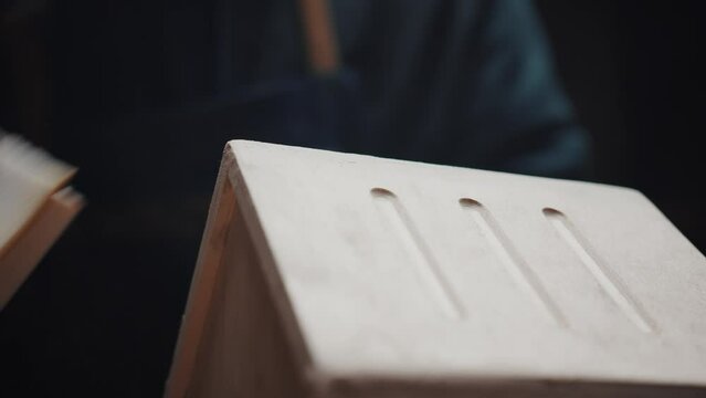 Craft production of wooden houses for birds and animals, family business in a carpentry workshop concept. Hands of an unrecognizable craftsman are polishing a wooden product