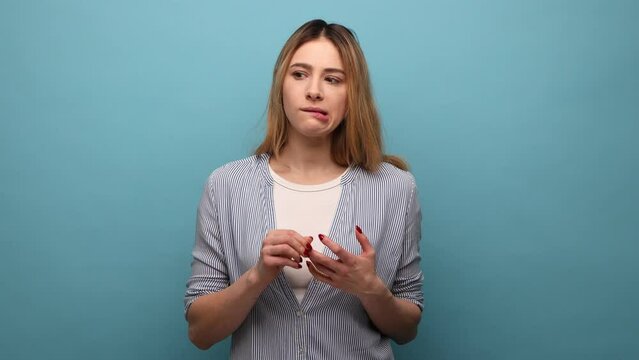 Portrait of thoughtful beautiful woman bending fingers, counting and looking with contemplation, calculation, wearing striped shirt. Indoor studio shot isolated on blue background.