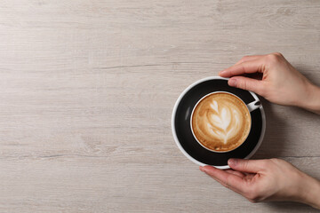 Woman with cup of aromatic coffee at wooden table, top view. Space for text