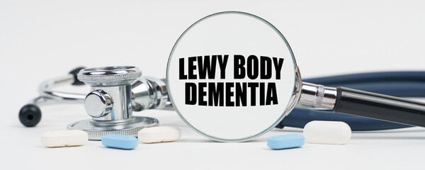 On a white surface are pills, a stethoscope and a magnifying glass inside which is written - Lewy body dementia