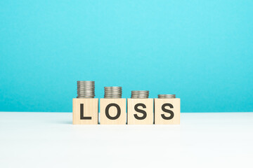 wooden blocks with text Loss and coins on wooden table. copy space. blue background