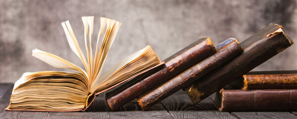 Vintage leather books stack on old rustic wooden surface