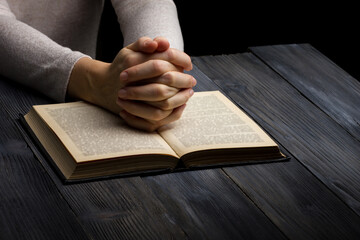 Prayer hand on Bible book on dark room
