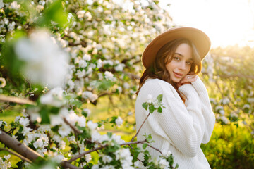 Young woman enjoying scent in blooming spring garden. The concept of relax, travel, freedom and...