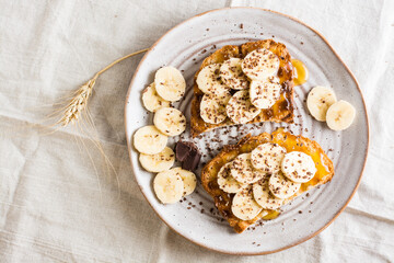 Ready to eat bruschettas with honey, banana and chocolate on a plate on the table. Vegetarian homemade snack. Top view. Close-up