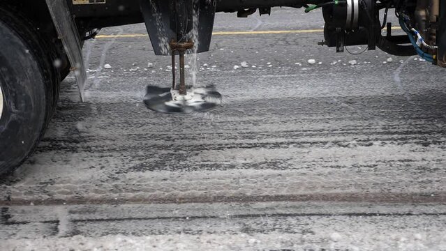 Truck mounted salter applying salt to snowy street. Toronto, Canada.