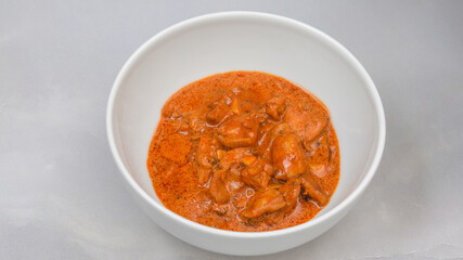 Hungarian paprikash, or meat with paprika and sour cream sauce close up in a bowl on marble background