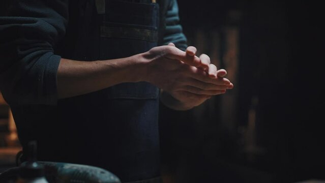 Cinematic video close-up of male hands shake off dust and shavings. A man completes work, men's work, male hobby concept. Young unrecognizable guy in workshop, dark key