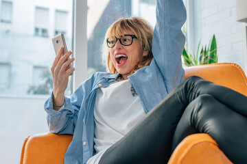 euphoric excited woman at home looking at mobile phone