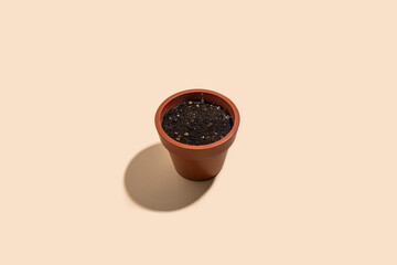 Brown pot for a flower with soil on a beige background. Top vew, flat lay.