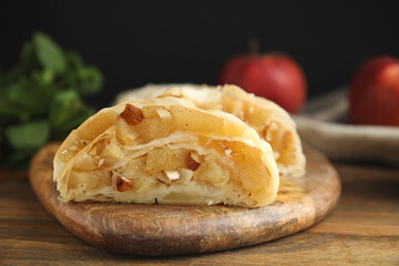 Delicious apple strudel with almonds on wooden table, closeup