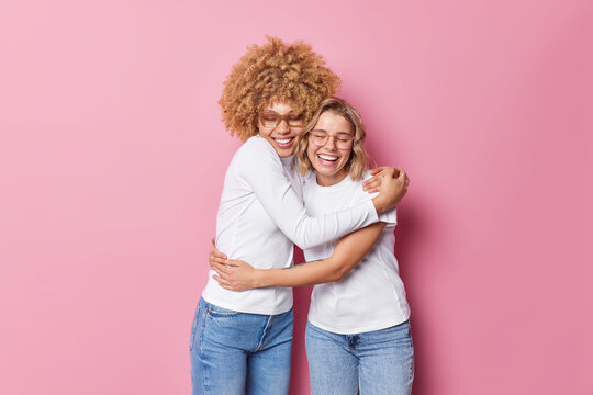 Friendly cheerful optimistic women embrace each other with love and smile gladfully have good relationship feel glad isolated over pink background. Friends spend family day together. Bonding concept