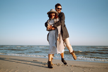 Stylish couple walking and hugging by the sea. Springtime. Relaxation, youth, love, lifestyle...