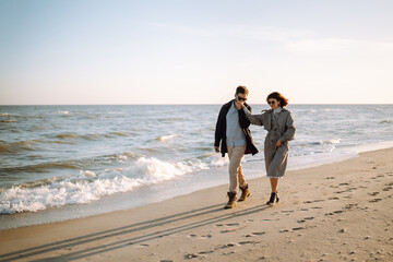 Stylish couple walking and hugging by the sea. Springtime. Relaxation, youth, love, lifestyle...