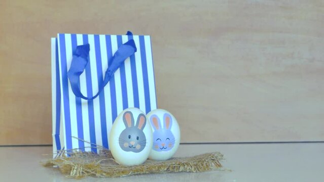 Easter eggs with a bunny pattern. Drawing with paints on a white egg. Woman's hand arranges pascal eggs