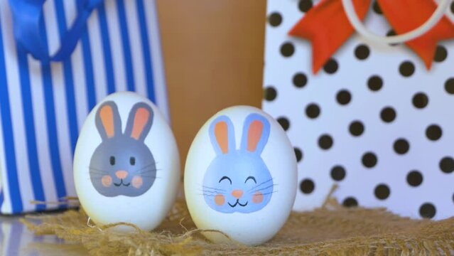 Easter eggs with a bunny pattern. Drawing with paints on a white egg. Woman's hand arranges pascal eggs