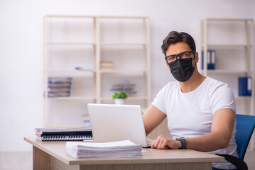 Young male student employee working at workplace during pandemic