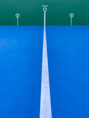 wall of a pediment court with blue floor with white marks with numbers for the pelota game, white line in the foreground, vertical