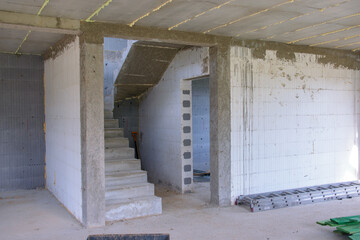 Remont domu. Budowa schodów. Surowe betonowe ściany.