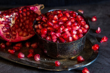 Fresh Pomegranate placed in old silver cup spoon full of seeds in dark and moody tone
