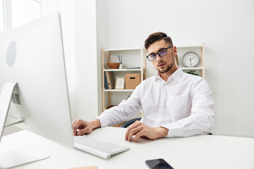 Fototapeta premium handsome businessman in a white shirt sits at a computer with a phone office