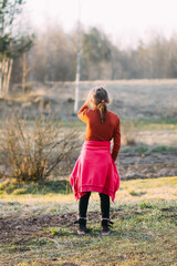 Fototapeta premium A little girl walks on the farm yard in a warm spring day. 