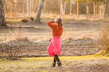 A little girl walks on the farm yard in a warm spring day. 