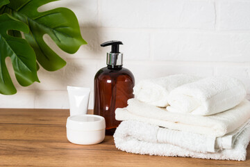 Fototapeta na wymiar Spa products in the bathroom. Bottle of soap, cosmetics and white towels in white bathroom.