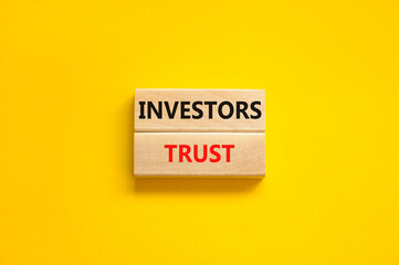 Investors trust symbol. Concept words Investors trust on wooden blocks on a beautiful yellow table...