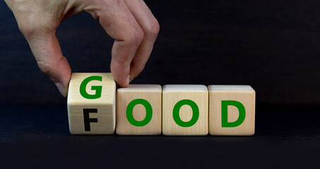 Good food symbol. Doctor turns a wooden cube and changes the word Food to Good. Beautiful grey table grey background. Lifestyle, healthy eating and good food concept, copy space.