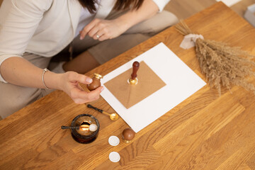 Cropped photo of woman hands making weeding invitation envelope craft, sitting at wood desk,...