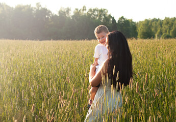 Mother holds her son in her arms and hugs. Happy family and parental love concept