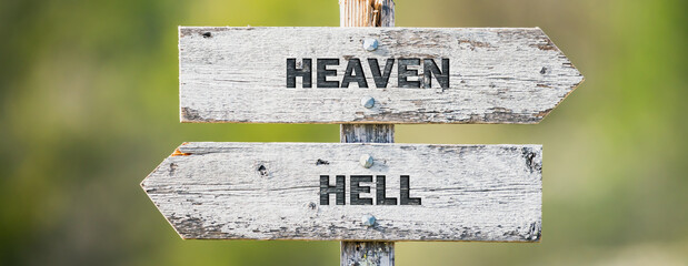 opposite signs on wooden signpost with the text quote heaven hell engraved. Web banner format.