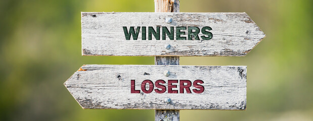 opposite signs on wooden signpost with the text quote winners losers engraved. Web banner format.