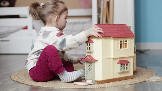 toddler girl playing with doll house at home