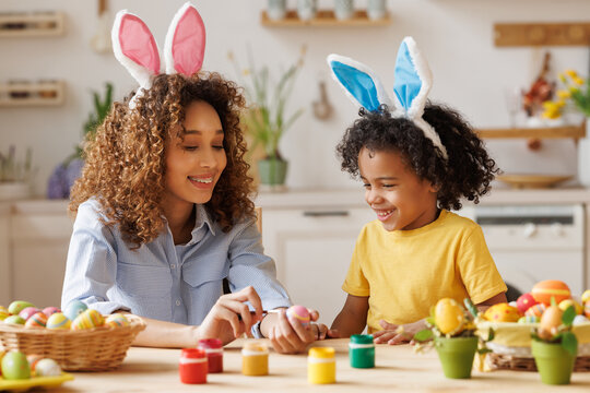 Happy African American Family: Mother Teaching Happy Little Kid Soon To Decorate Easter Eggs While Sitting In Kitchen