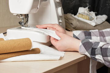 a woman sews a shopping bag made of cotton and cork with a sewing machine