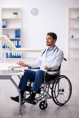 Young male doctor in wheel-chair working in the clinic
