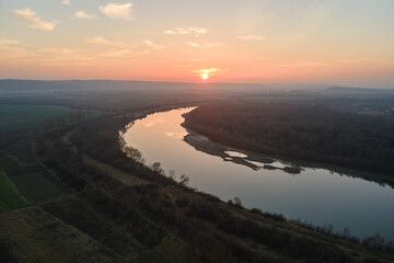 Aerial view of wide river flowing quietly in rural countryside in autumn evening