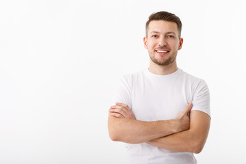 Portrait of a cheerful young man in a white T-shirt on a white background. The guy is standing looking at the camera and smiling.