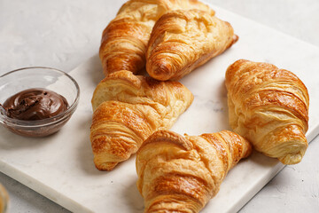 several freshly baked french butter croissants on marble tray with hazelnut spread