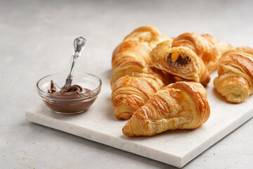 several freshly baked french butter croissants on marble tray with hazelnut spread
