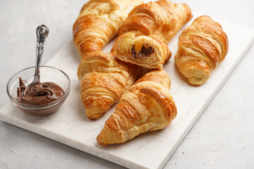 several freshly baked french butter croissants on marble tray with hazelnut spread