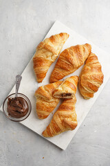 several freshly baked french butter croissants on marble tray with hazelnut spread, top view