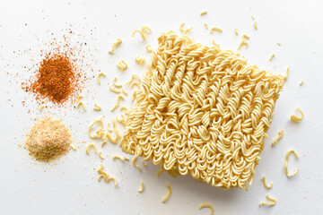 Instant noodles with seasonings on the table.  Uncooked noodles with dried red chilli flakes and ingredients on white.  Flat lay top view food photography.  Food from above concept.