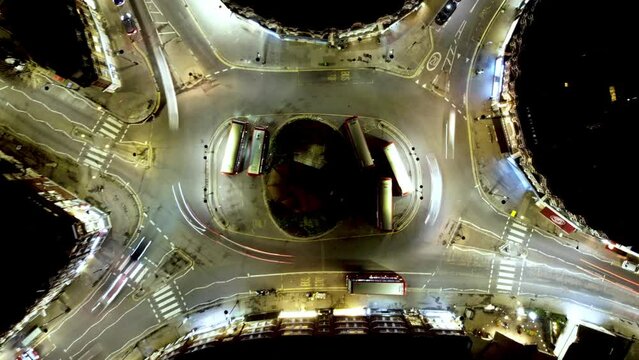 Timelapse of busy London roundabout with traffic racing round congested area at night, from drone high above scene