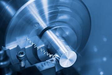 Lathe tool bit and spiral swarf at working on metal product in blue toned background. Closeup of steel knife with carbide insert in holder of turning machine. Chip machining with motion blur or bokeh. - obrazy, fototapety, plakaty